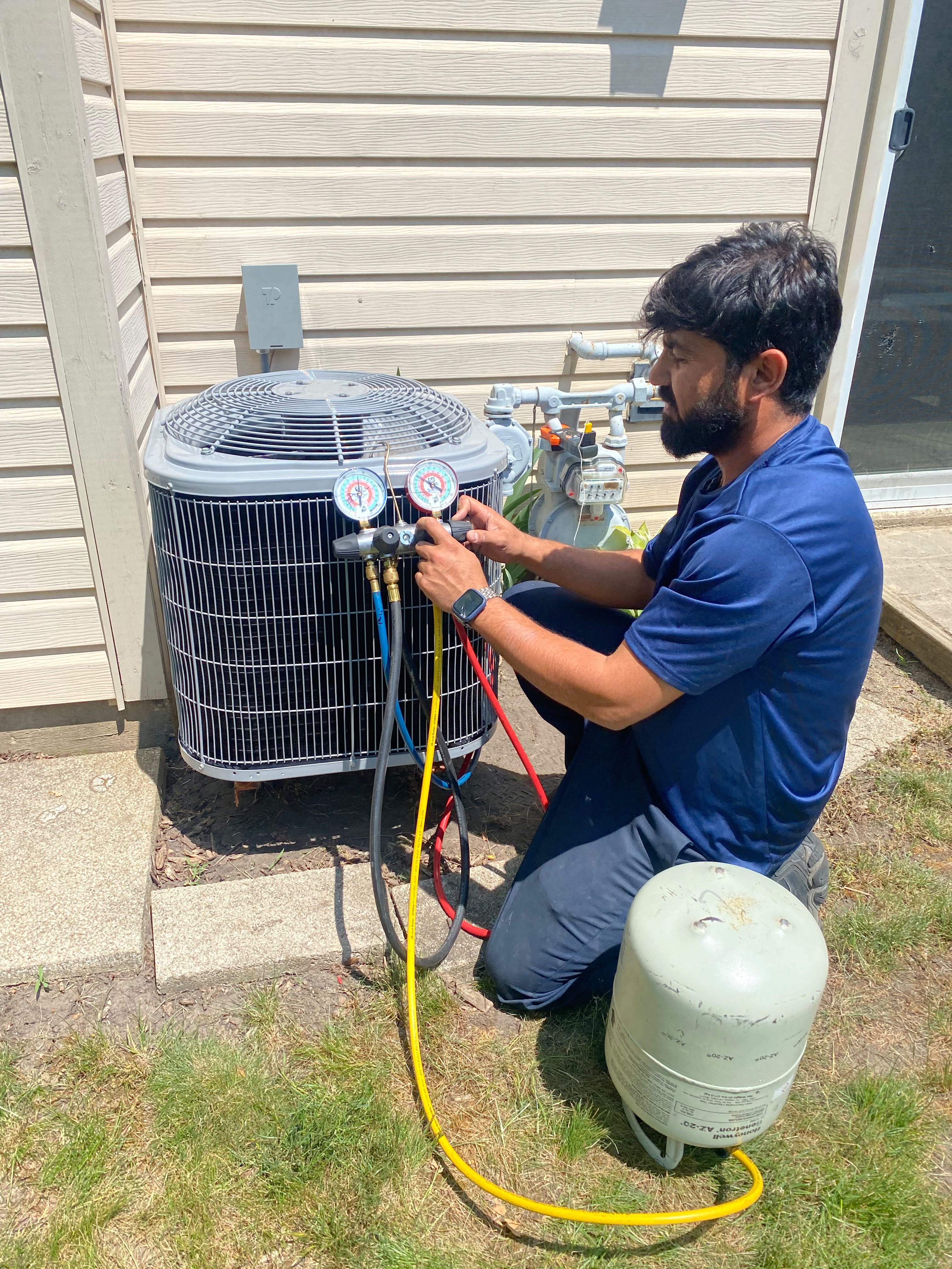 Ali HVAC technician servicing an outdoor air conditioning unit